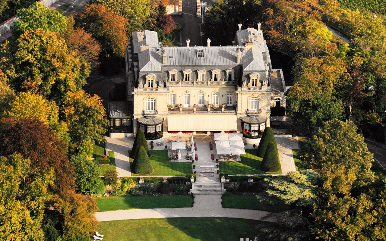 Vue aérienne du château des Crayères, ses toits d'ardoise, ses terrasses et son parc arboré aux couleurs d'automne