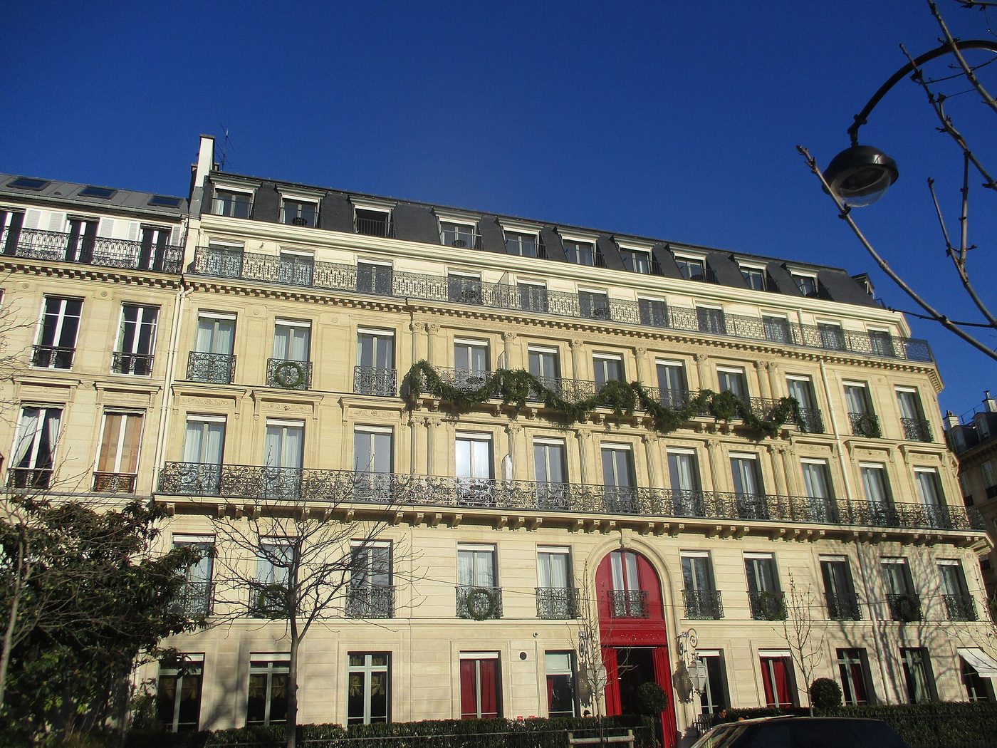 La façade claire de La Réserve Paris, avenue Gabriel, avec ses balcons en fer forgé et sa porte rouge