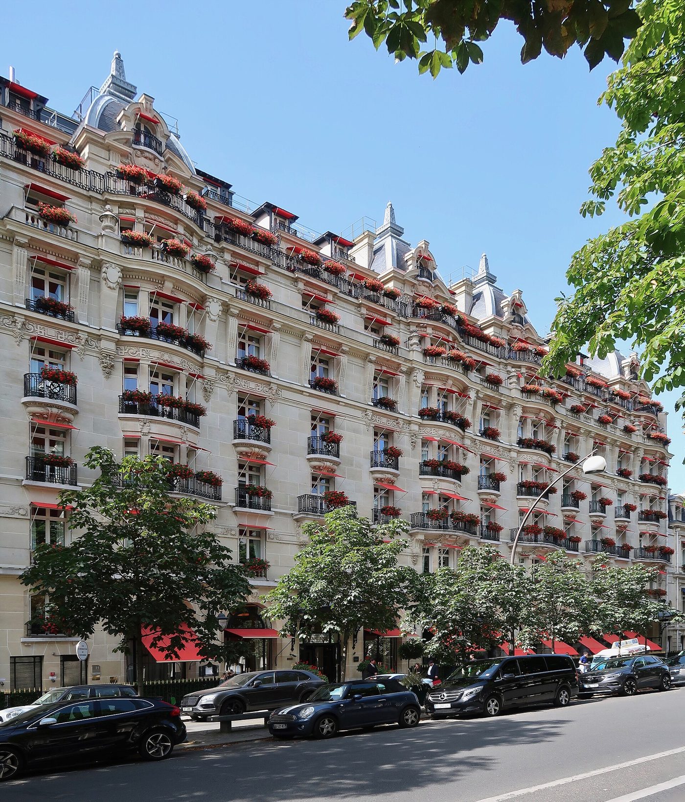 La façade du Plaza Athénée, avenue Montaigne, avec ses balcons fleuris de rouge et ses auvents rouges