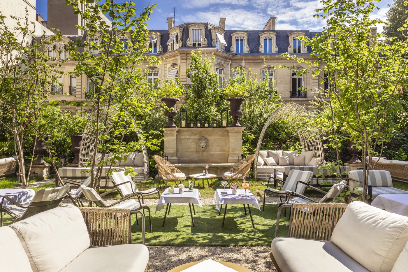 Le jardin d'Apicius, salons de jardin et tables nappées sur la pelouse, devant la façade de l'hôtel particulier