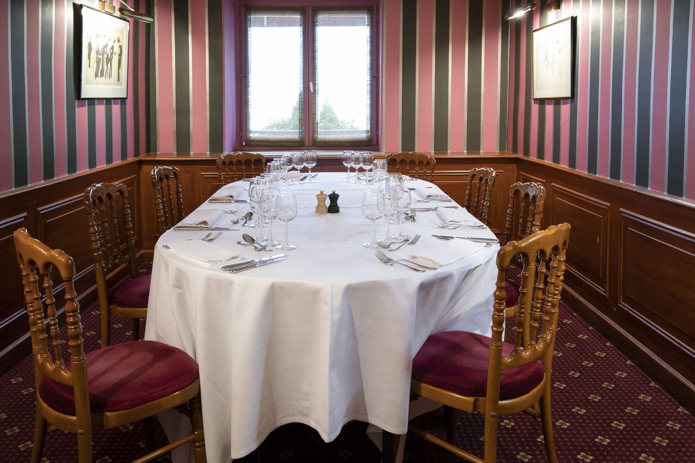 Un salon privé d'Au Petit Riche, table ovale nappée de blanc, chaises dorées à coussins grenat, murs rayés