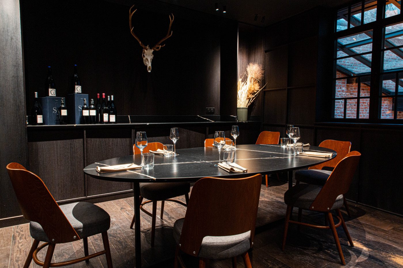 La salle du Braque, tables de bois sombre, chaises et lumières tamisées sous un plafond noir