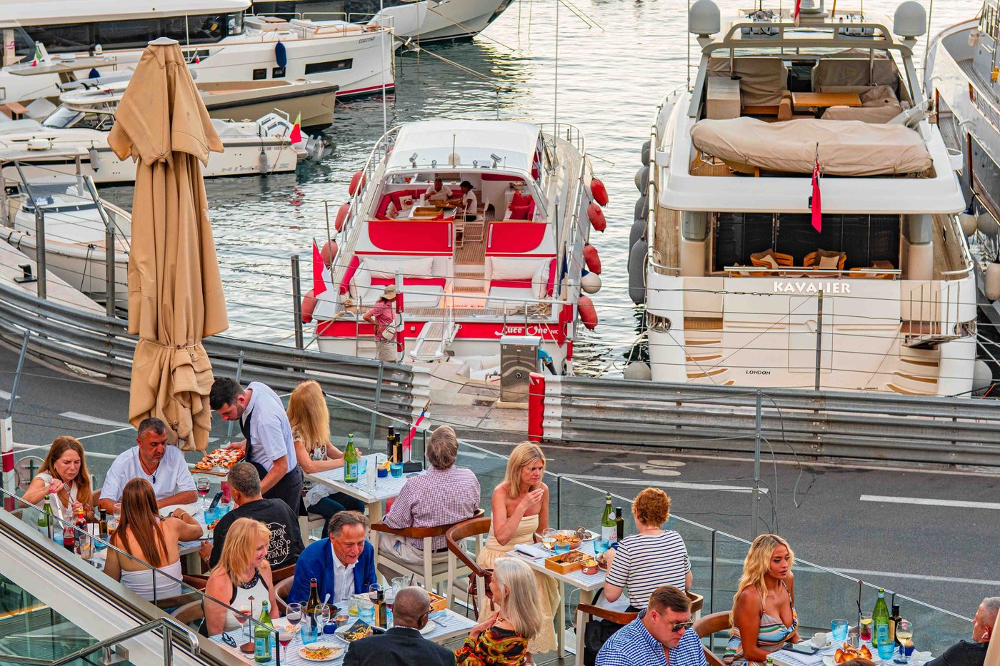 La terrasse de Caffè Milano au bord du port Hercule, tables dressées et yachts amarrés juste derrière