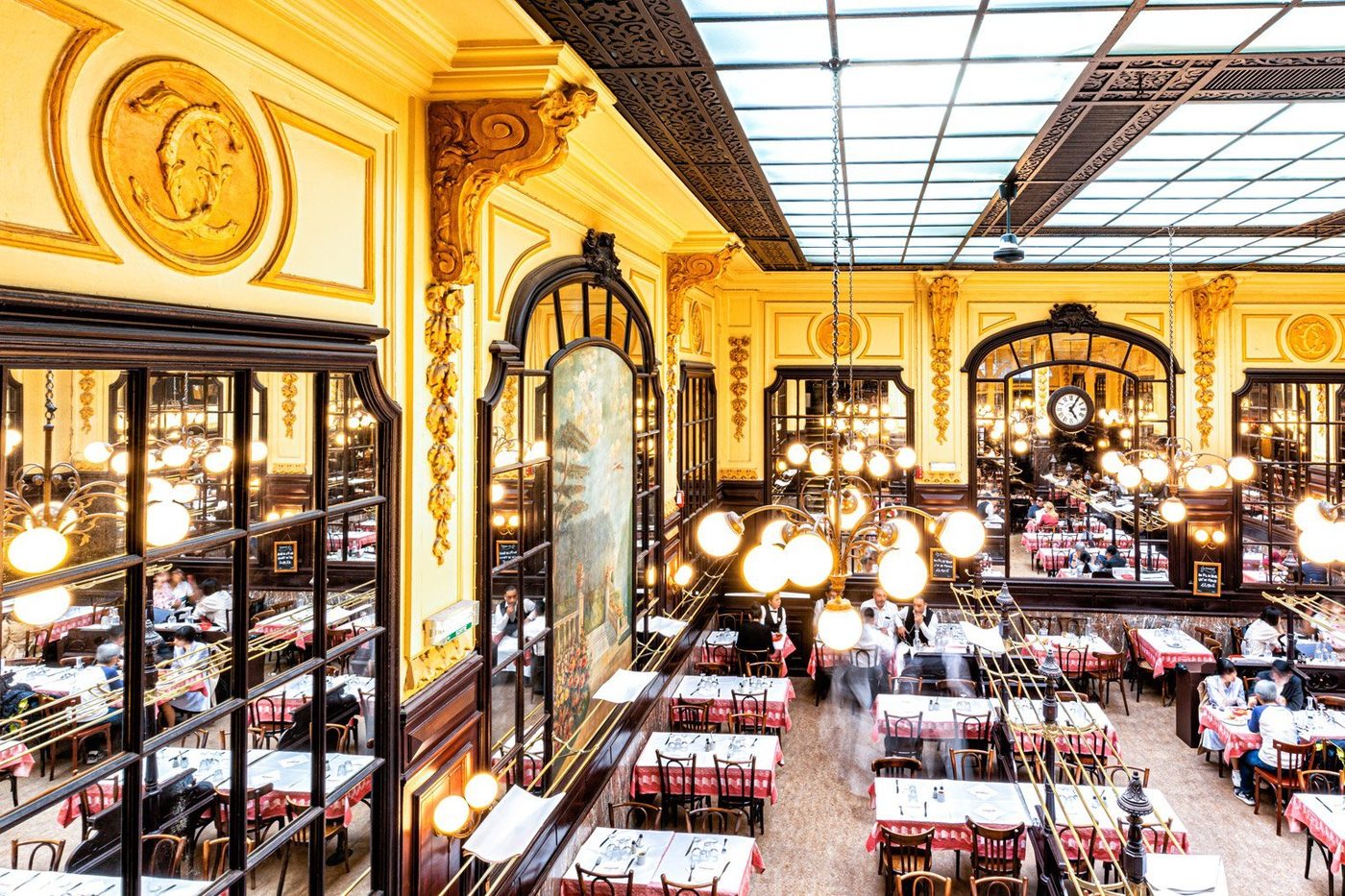 La grande salle de Chartier vue d'en haut, verrière, boiseries, lustres à globes et rangées de tables