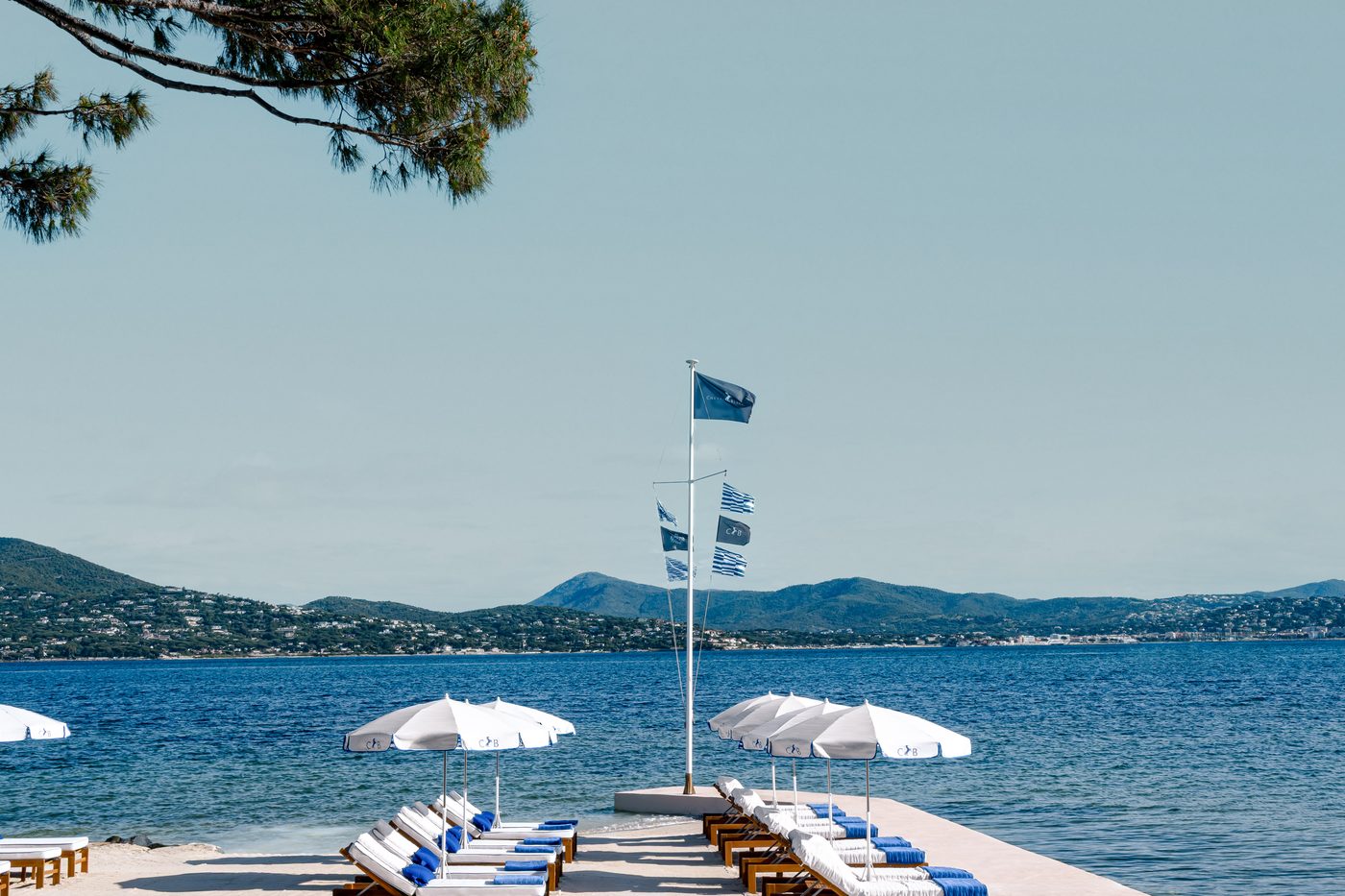La plage du Cheval Blanc St-Tropez, parasols blancs et transats bleus face au golfe