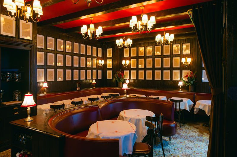 La salle de Chez Miocque, banquettes rouges, tables nappées, lustres et murs couverts de cadres