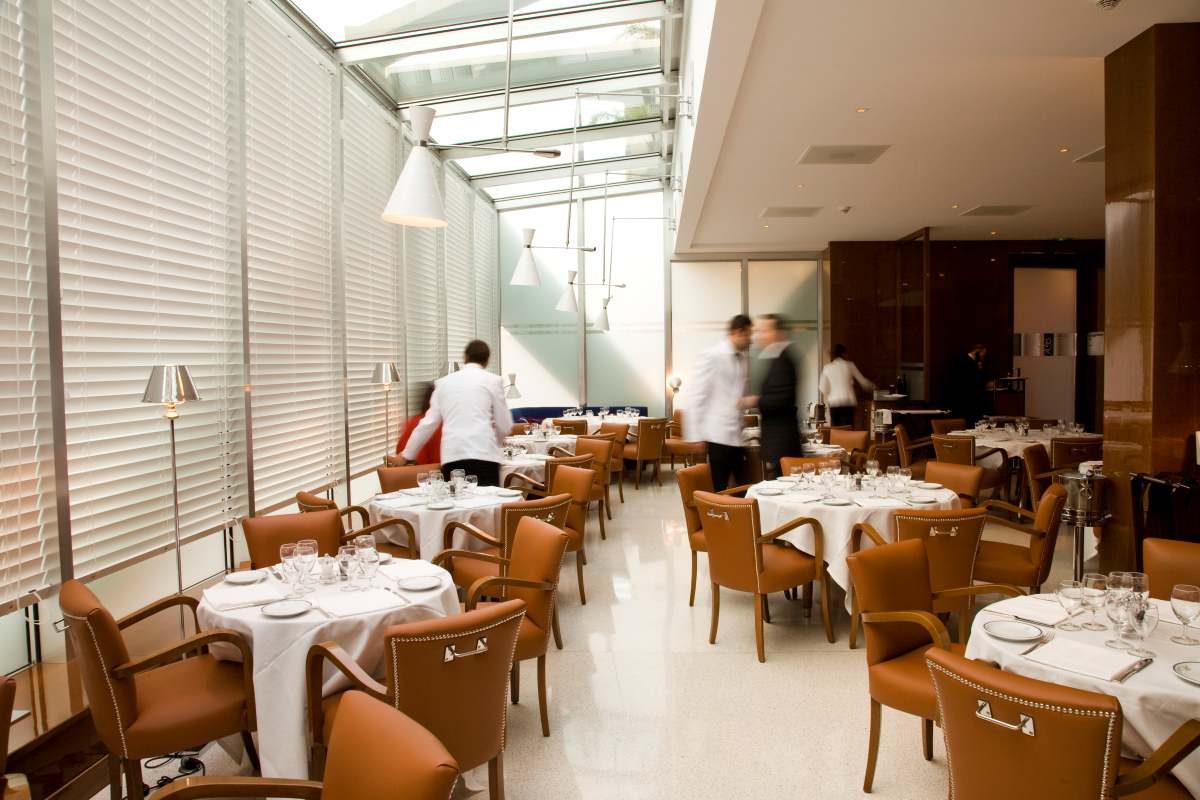 La salle de Cipriani Monte-Carlo, tables rondes nappées de blanc, fauteuils de cuir et stores clairs