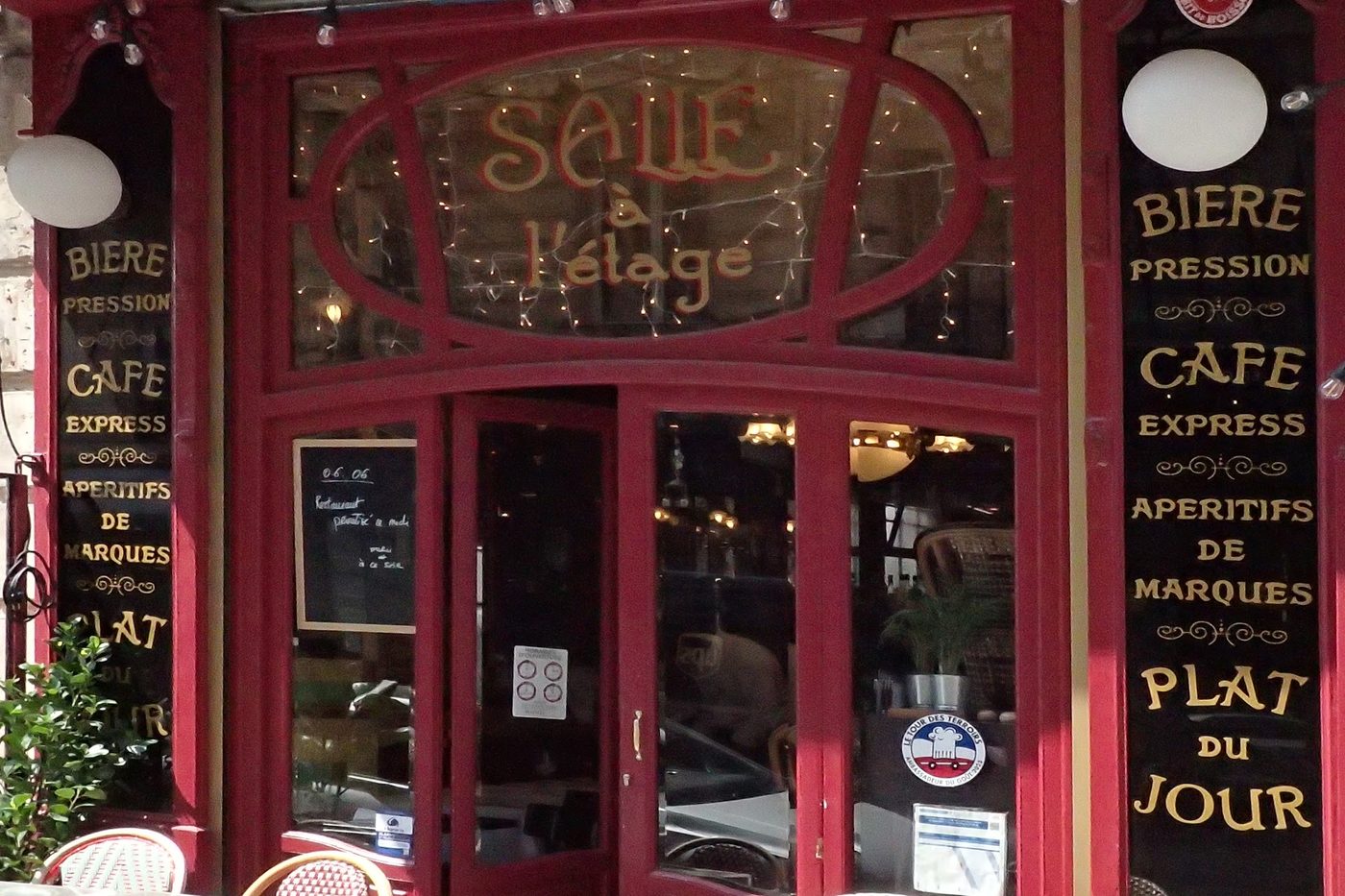 La devanture rouge du Cochon à l'Oreille, panneaux « Bière pression », « Café express » et « Plat du jour »