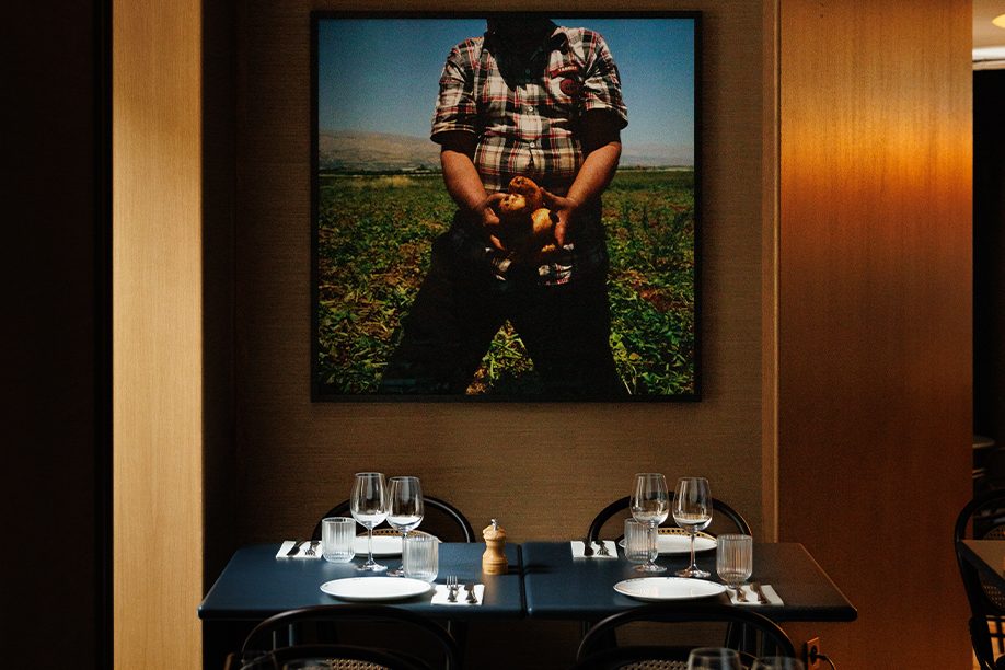 Une table d'Em Sherif Café, chaises noires cannées et mur de bois sous une grande photographie