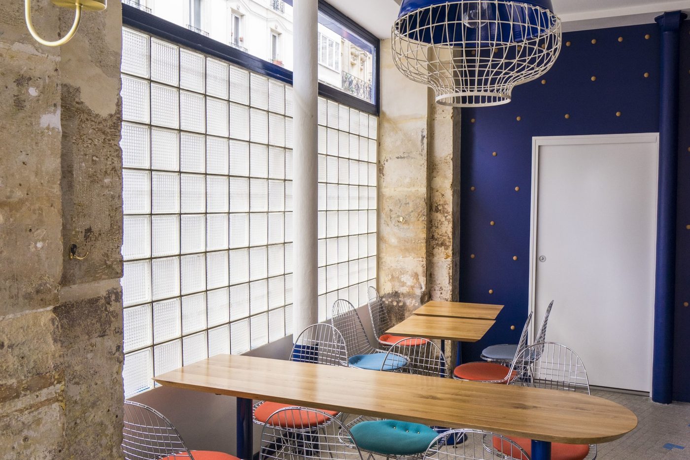 La salle de Fichon : mur de pierre, pavés de verre, table de bois et chaises de fil aux coussins colorés