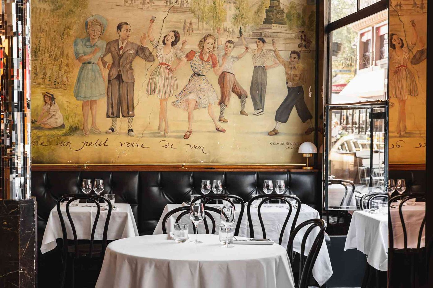 La salle de la Grande Brasserie : banquettes de cuir noir, tables nappées et grande fresque de danseurs au mur