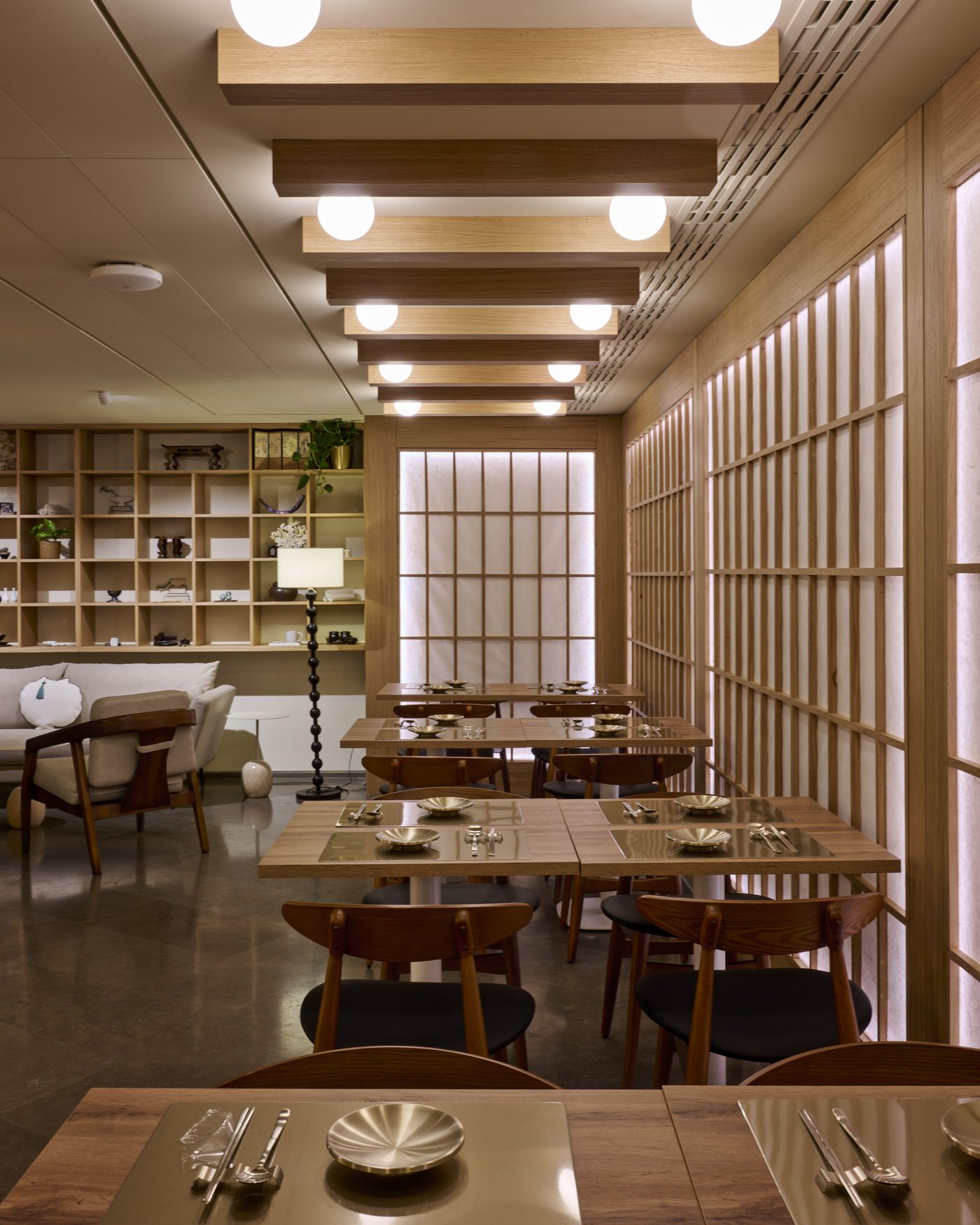 La salle de Hanok au musée Guimet, tables et chaises en bois clair sous des panneaux lumineux à croisillons
