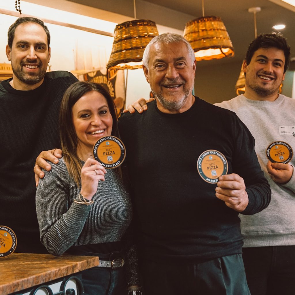 L'équipe d'Il Giardino dans sa salle aux suspensions d'osier, tenant les macarons Best Pizza 2024
