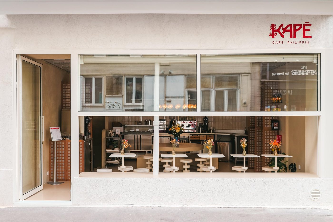 La façade blanche de KAPÉ, enseigne rouge « café philippin » et grande vitrine sur la salle