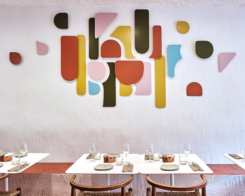 La salle de Kubri, avec ses tables blanches et son mur orné de formes colorées