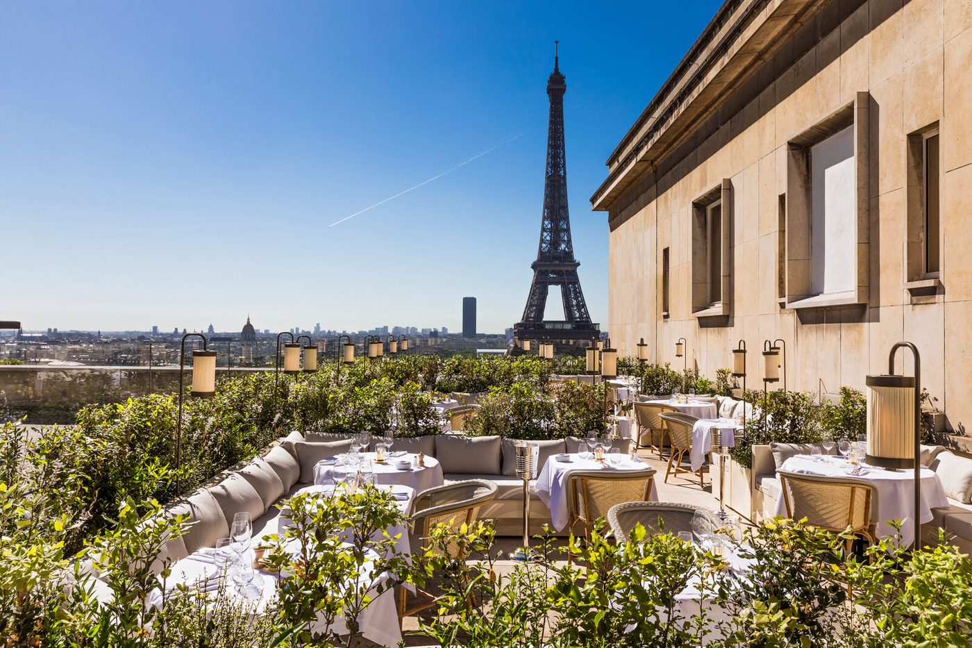 La terrasse de La Suite Girafe, banquettes crème et tables nappées, face à la tour Eiffel
