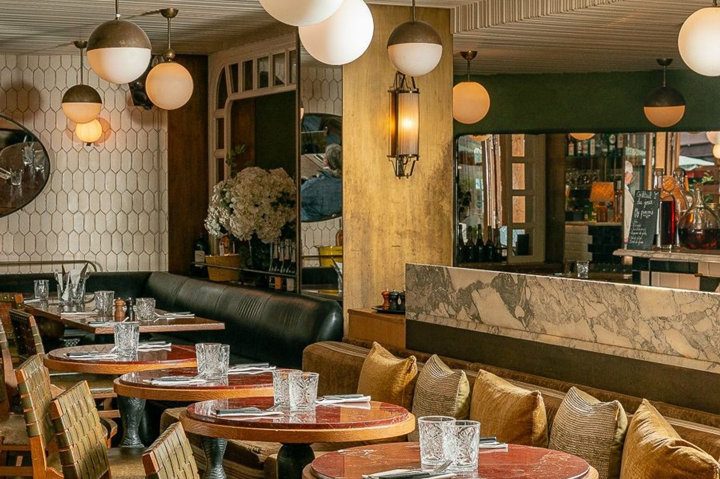 La salle du Bois, banquettes vertes, suspensions en globes, tables rondes et comptoir de marbre