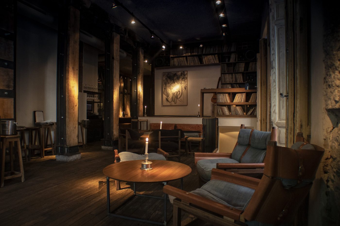 Le salon de Los 33, fauteuils de cuir, lampe à poser et étagères dans une lumière tamisée