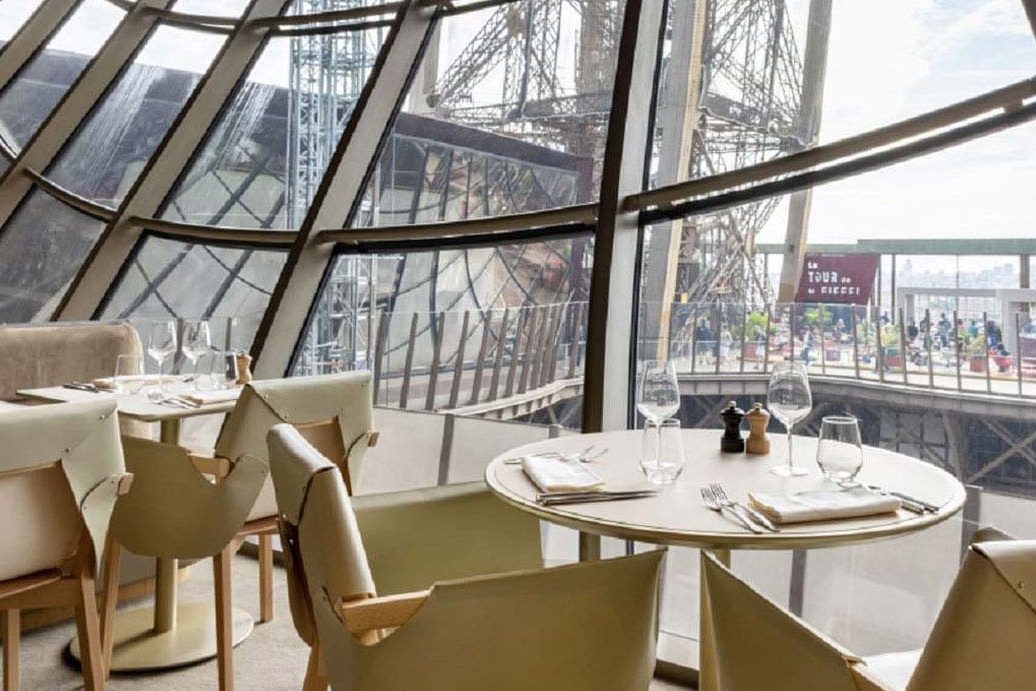 La salle de Madame Brasserie sous les grandes vitres inclinées, la charpente de fer de la tour Eiffel derrière
