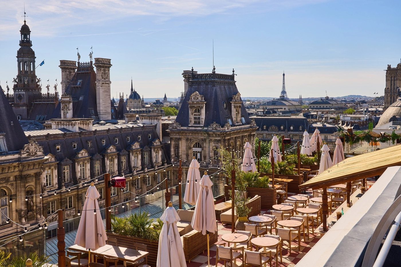 Le rooftop de Terraza Mikuna, tables en bois et parasols fermés, les toits de l'Hôtel de Ville et la tour Eiffel