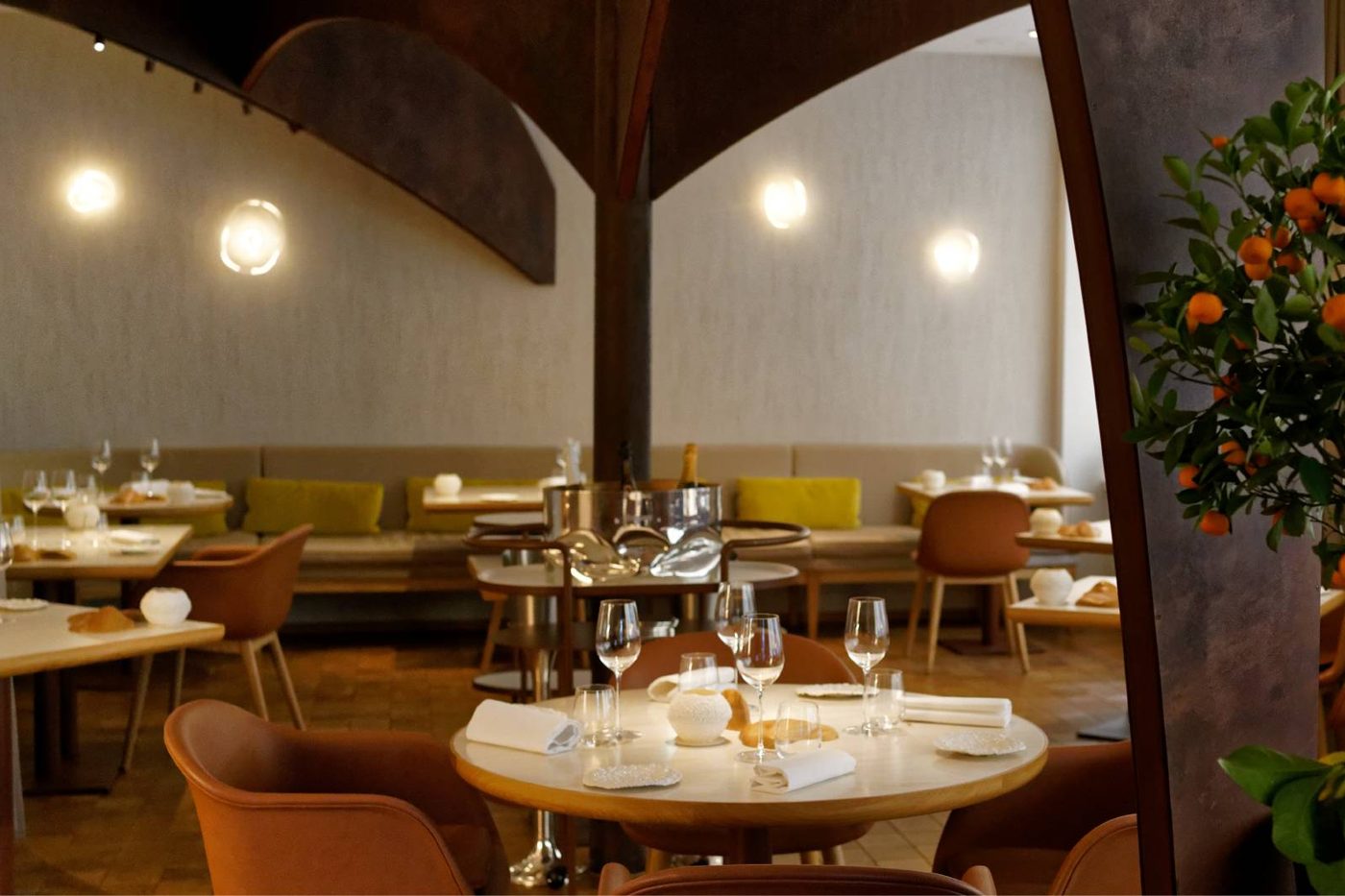 La salle de Nomicos, arches en acier corten, tables nappées de blanc et fauteuils de cuir caramel