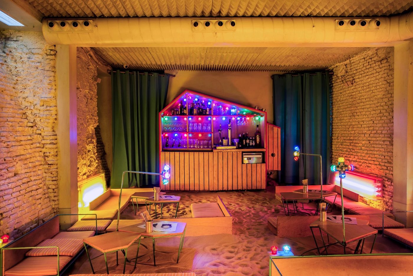 La salle du sous-sol d'Ojalá, au sol couvert de sable blanc, coussins et tables basses