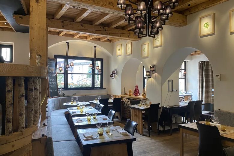 La salle du Prieuré, arcades blanches, poutres, lustre en fer forgé et tables dressées