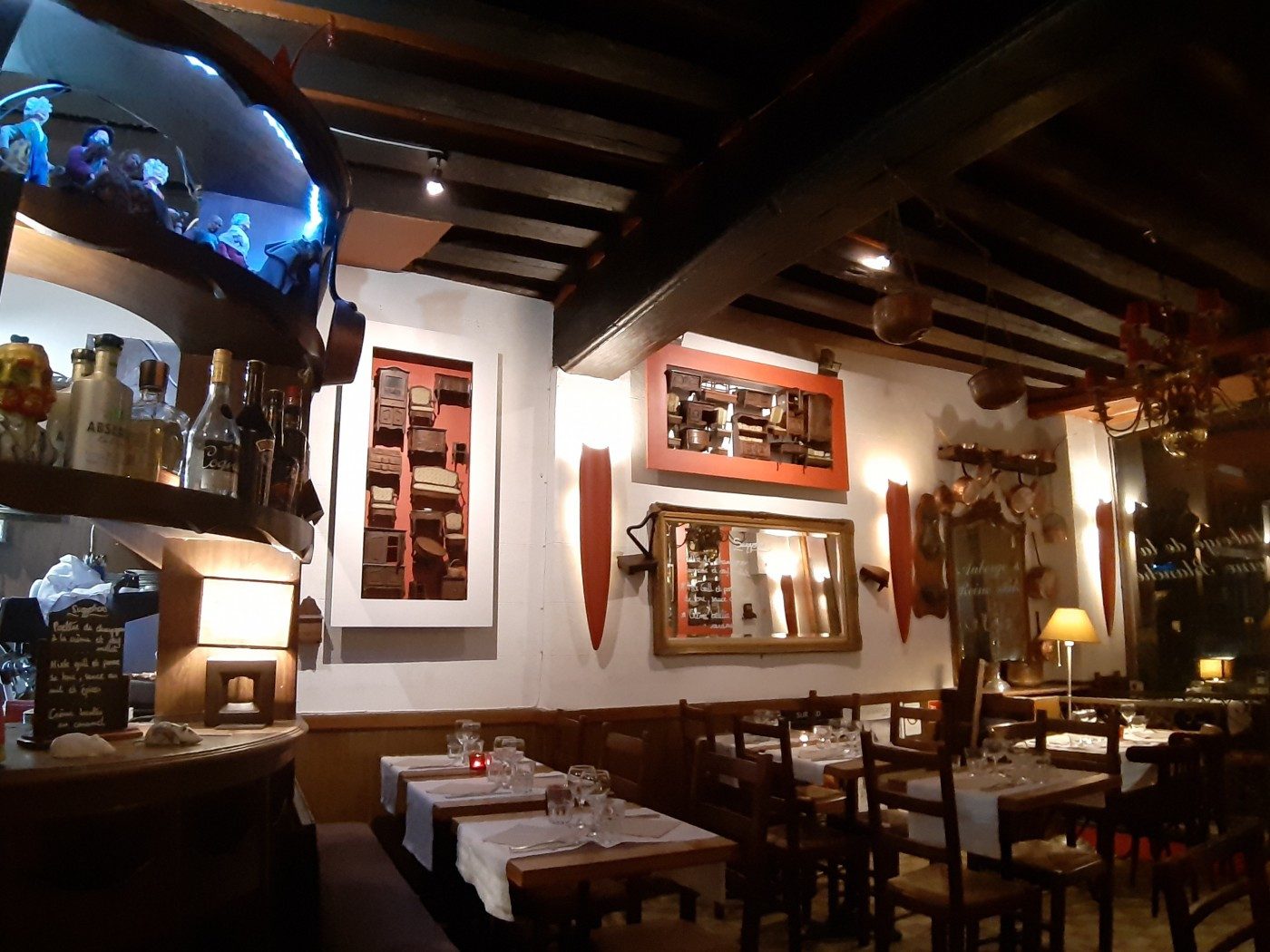 La salle de l'Auberge de la Reine Blanche, poutres sombres, murs clairs, tableaux et tables dressées