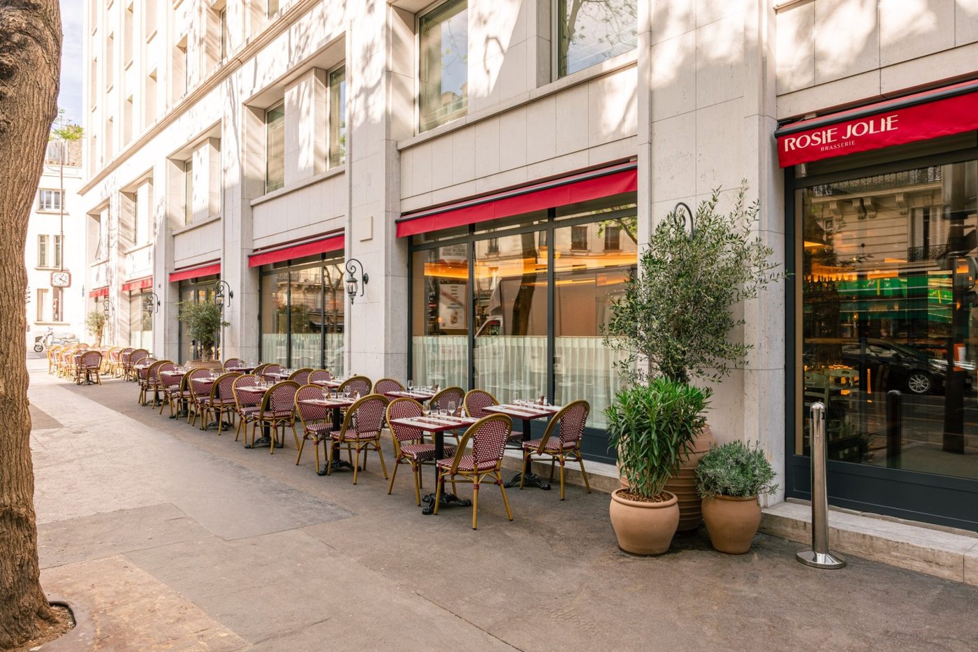 La façade de Rosie Jolie, stores rouges et longue terrasse de chaises en rotin le long du trottoir