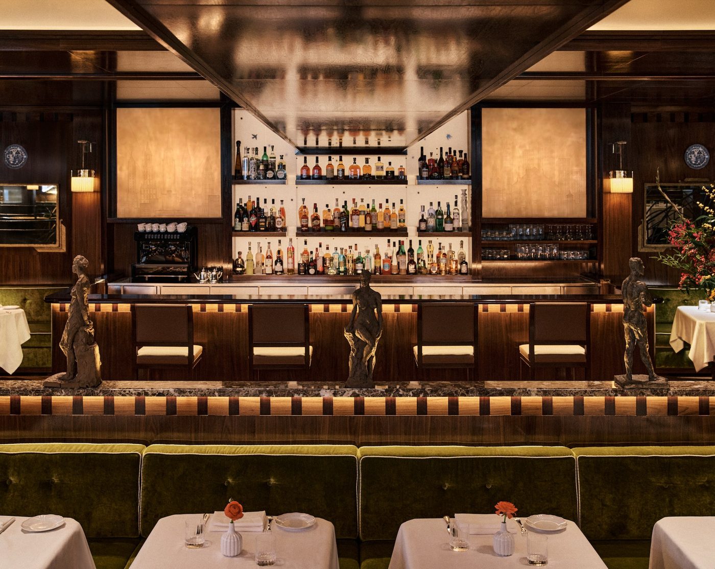 Le bar de Sant Ambroeus Paris, étagères rétroéclairées, boiseries sombres et banquettes de velours vert