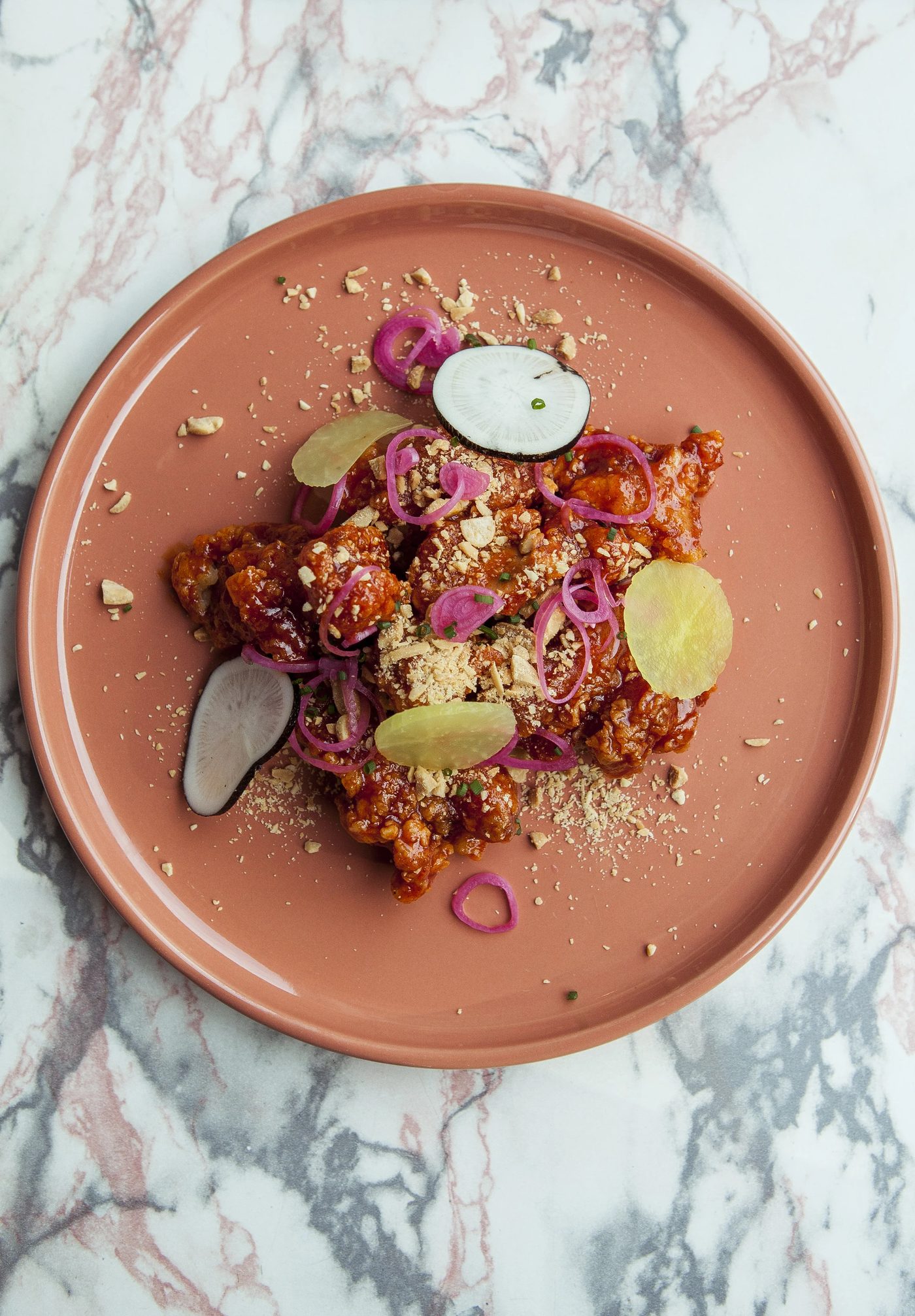 Une assiette de poulet frit coréen, radis en pickles et cacahuètes concassées, chez Seoul Mama