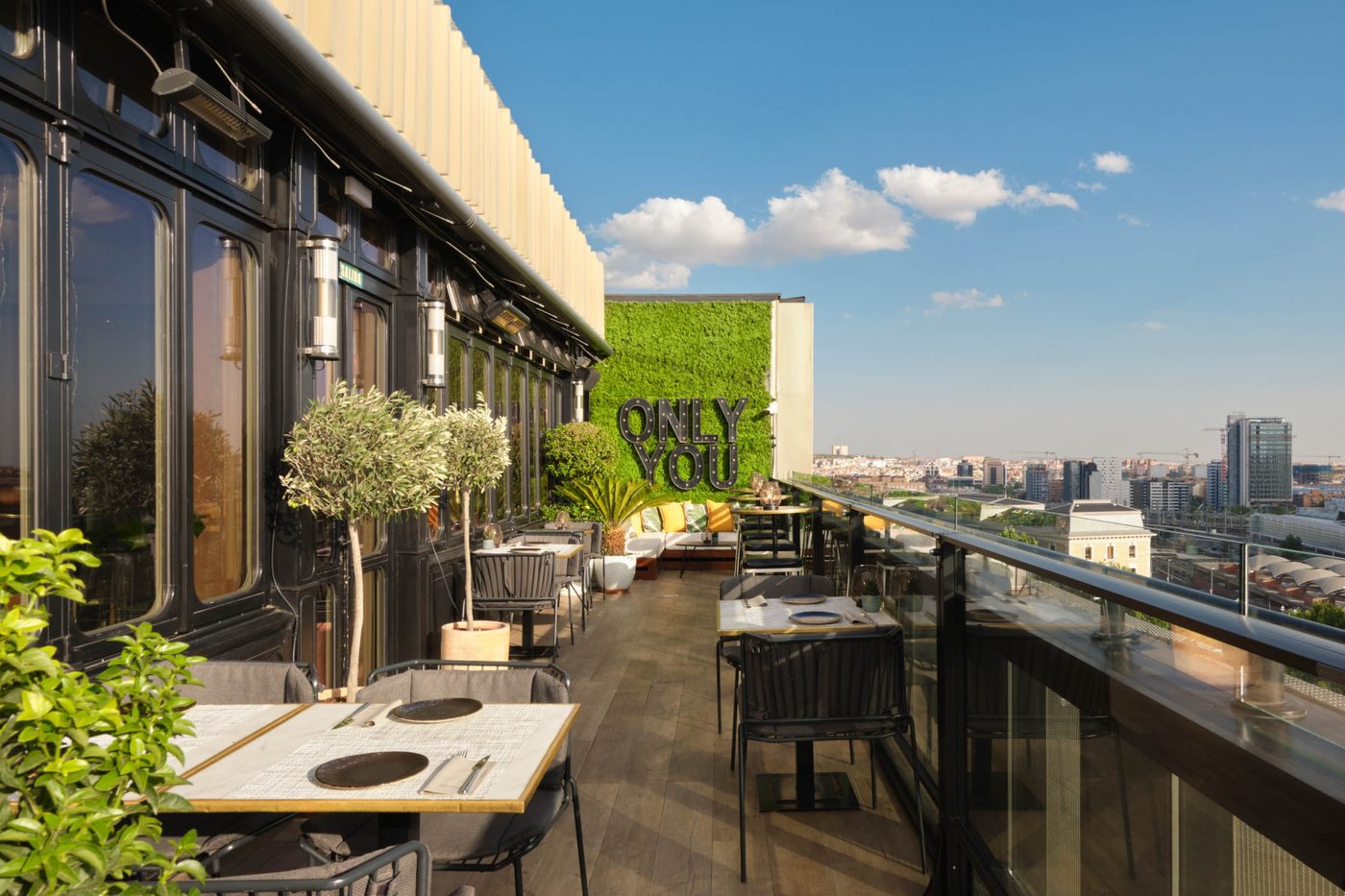 La terrasse du Sép7ima au septième étage de l'Only YOU Atocha, tables dressées, oliviers en pot et chauffages