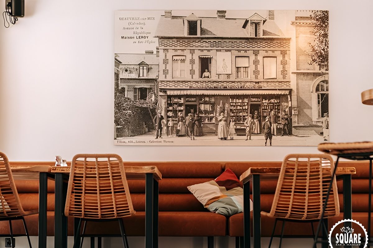 Une banquette de cuir sous une grande photo ancienne de Deauville, chaises de rotin, au Square
