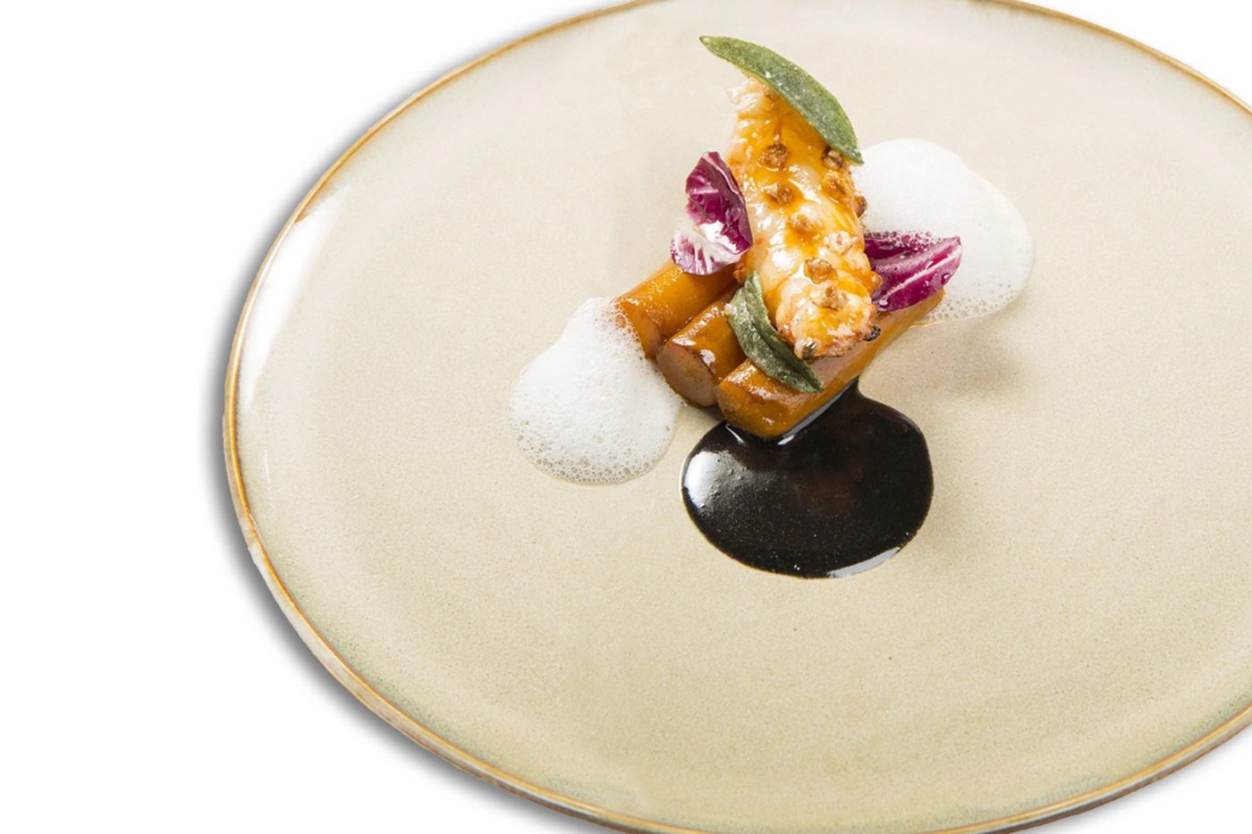 Une assiette de La Table du Clarance, mise en bouche dressée sur une sauce sombre dans une assiette crème