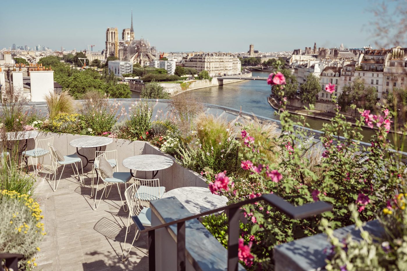 La terrasse du Toit de la Tour, tables rondes en marbre et jardinières fleuries au-dessus de la Seine