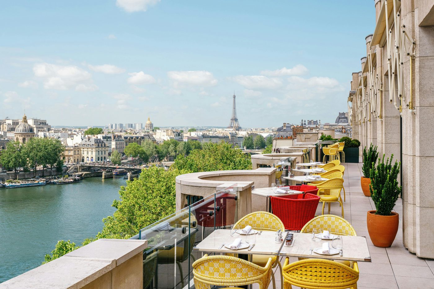 La terrasse du Tout-Paris, chaises tressées jaunes, au-dessus de la Seine, avec la tour Eiffel à l'horizon