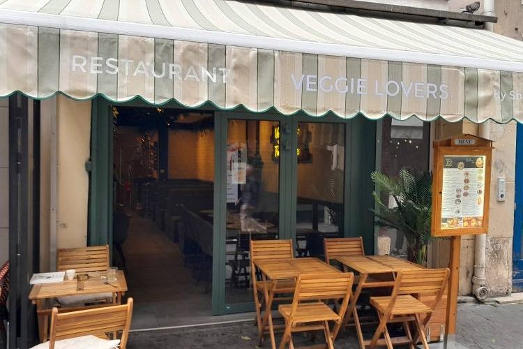 La façade de Veggie Lovers, rue Saint-Martin, son store rayé et sa terrasse de tables en bois
