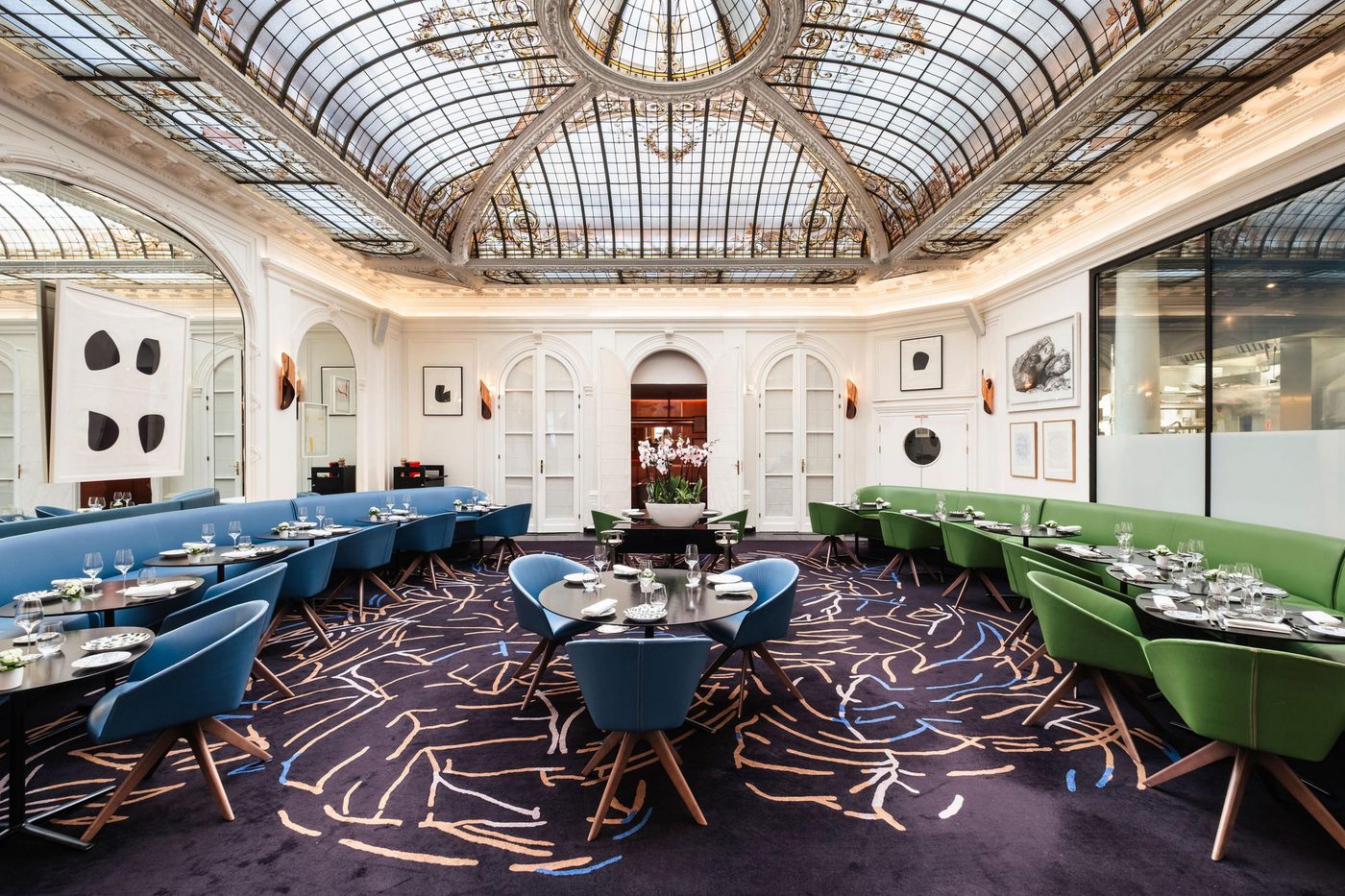 La salle du V sous la verrière de l'hôtel Vernet, banquettes bleues et vertes, tables dressées