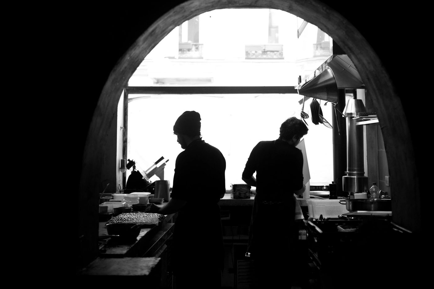 Deux cuisiniers de Vivide en contre-jour, encadrés par une arche, dans leur cuisine
